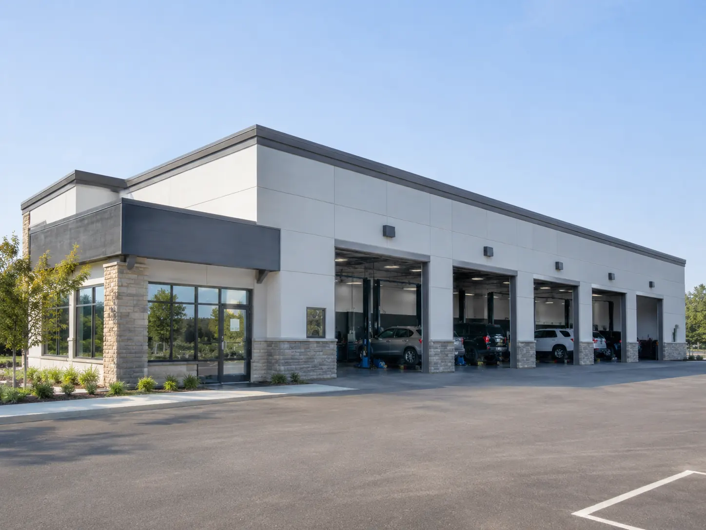 An automotive service building with open repair bays and vehicles inside.